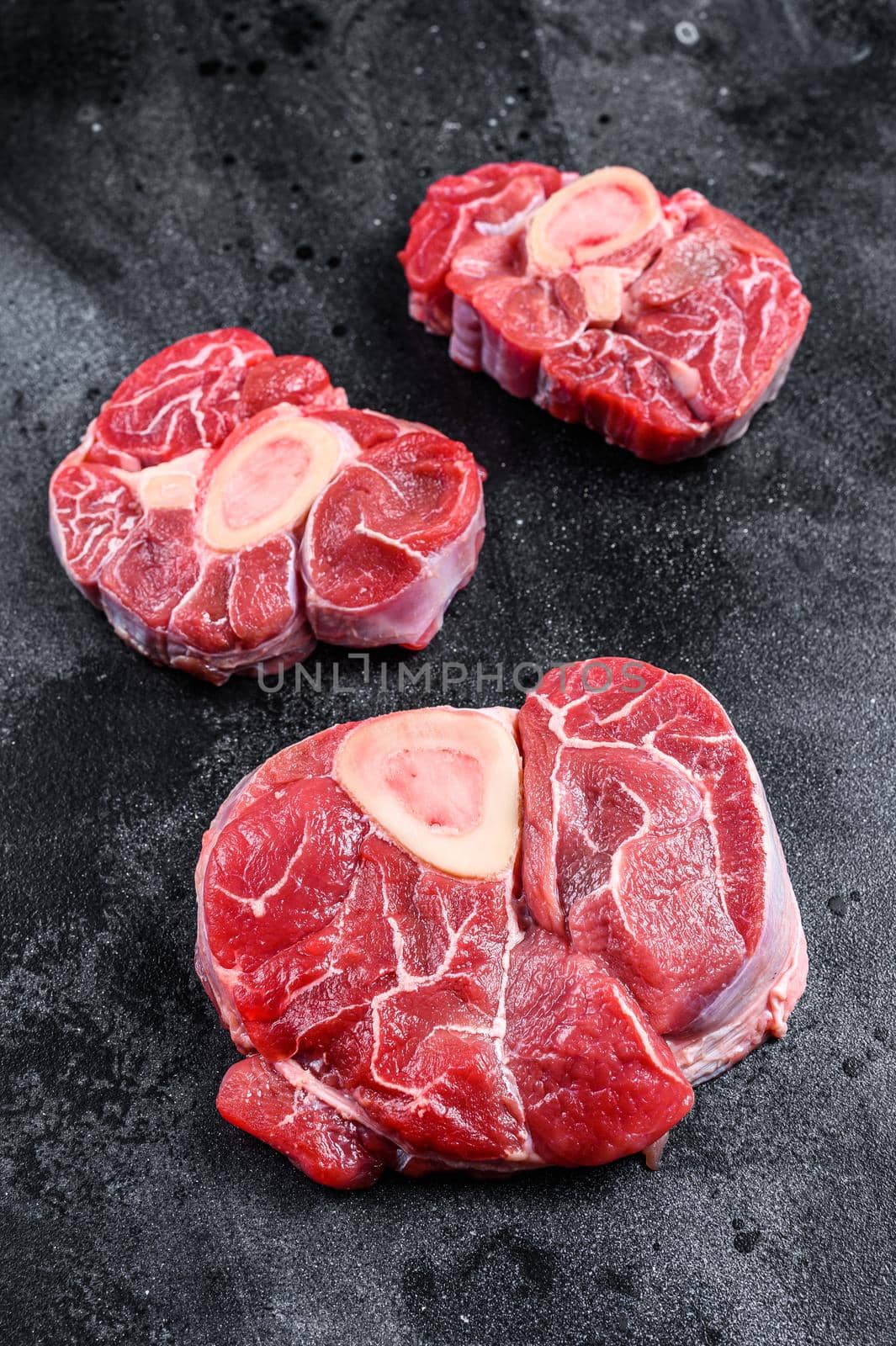 Fresh veal meat osso buco shank steak, italian ossobuco. Black background. Top view by Composter