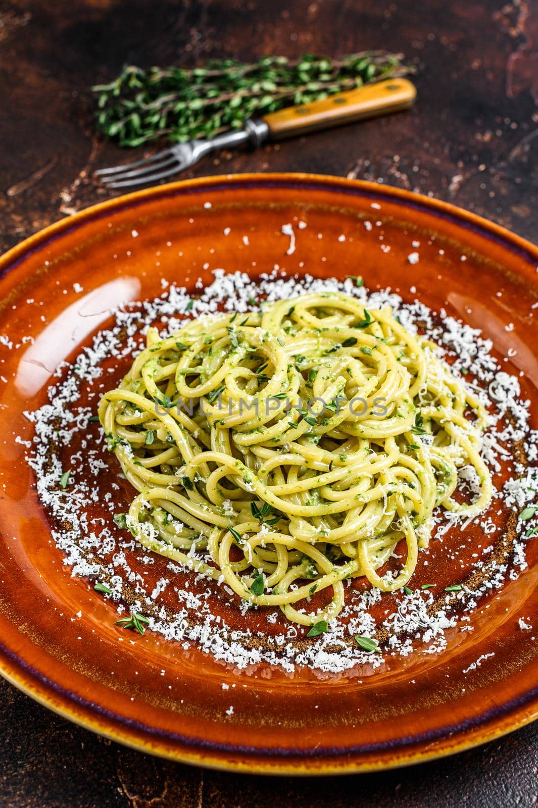 Spinach Spaghetti Pasta with pesto sauce and parmesan. Dark background. Top view.