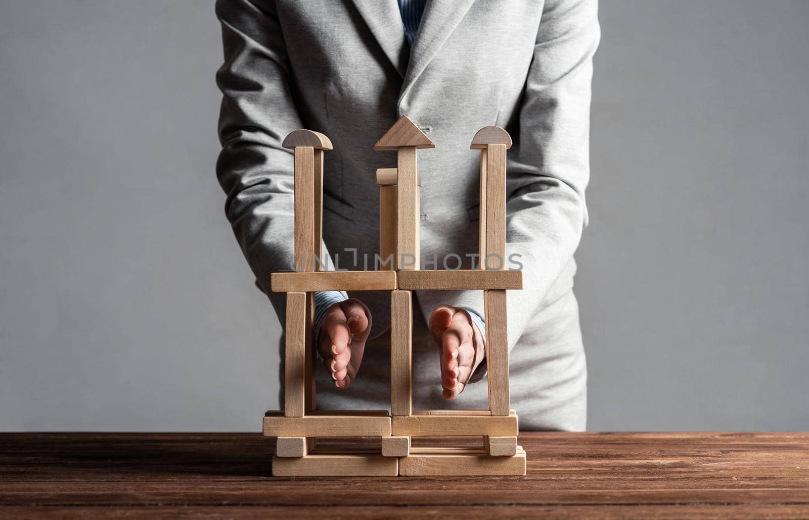 Business woman building construction on table from wooden blocks. Strategy planning and company development. Young woman wearing formal wear sitting in office interior. Business motivation concept