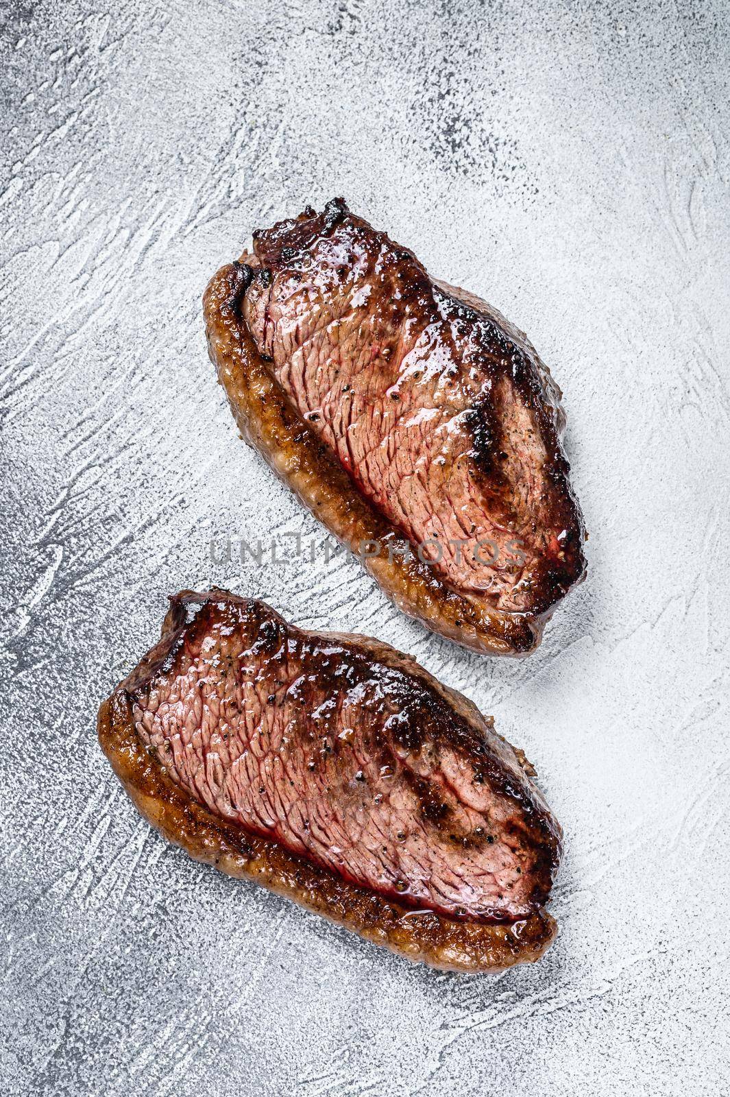 Grilled top sirloin cap or picanha steak. White background. Top view by Composter
