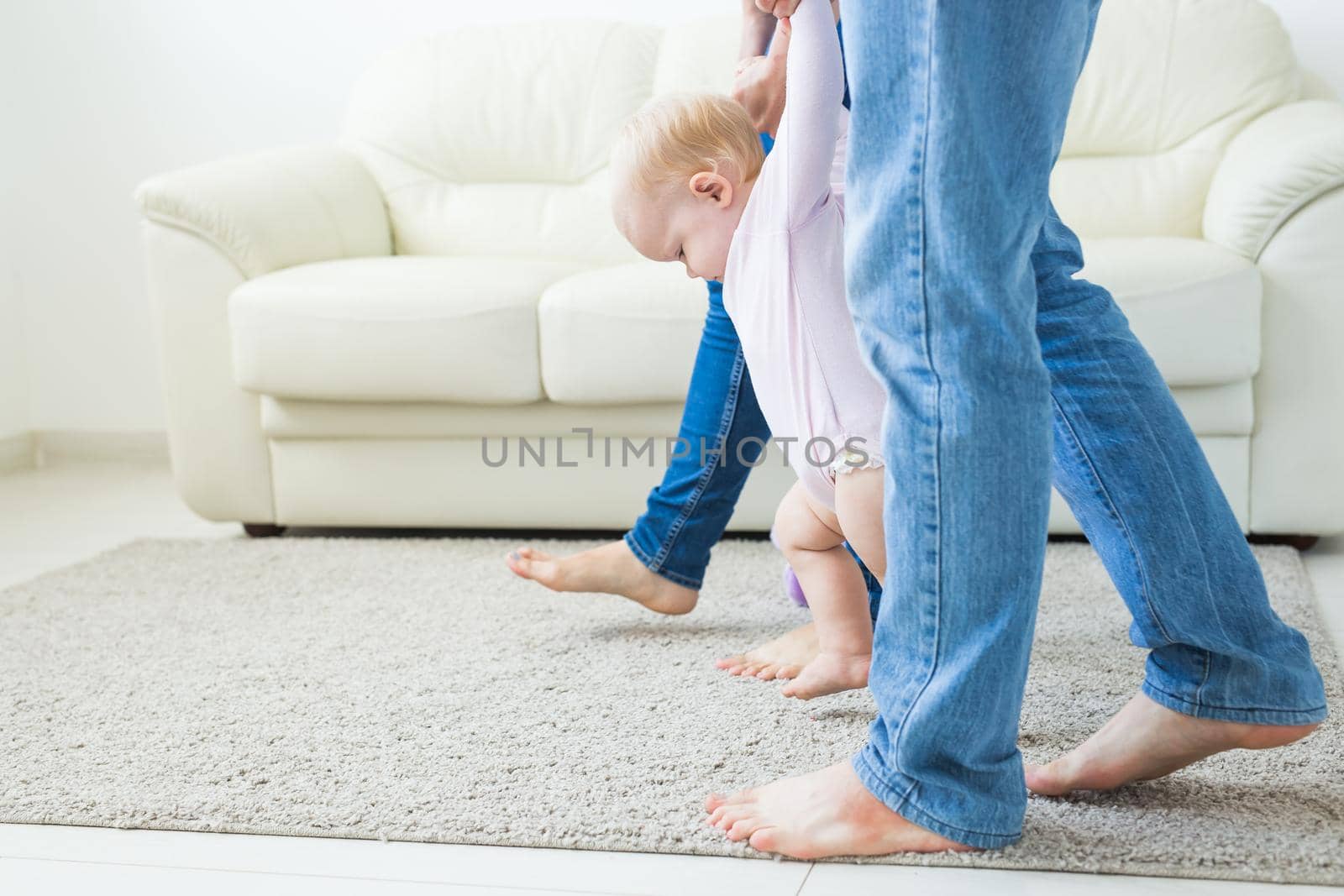 First steps of baby toddler learning to walk in white sunny living room. Footwear for child