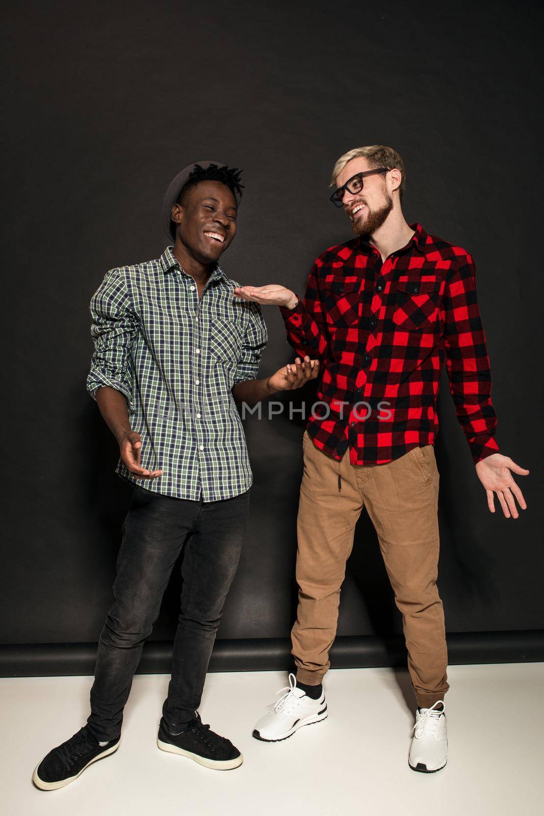 Studio lifestyle portrait of two best friends hipster boys going crazy and having great time together. On black background. by nazarovsergey