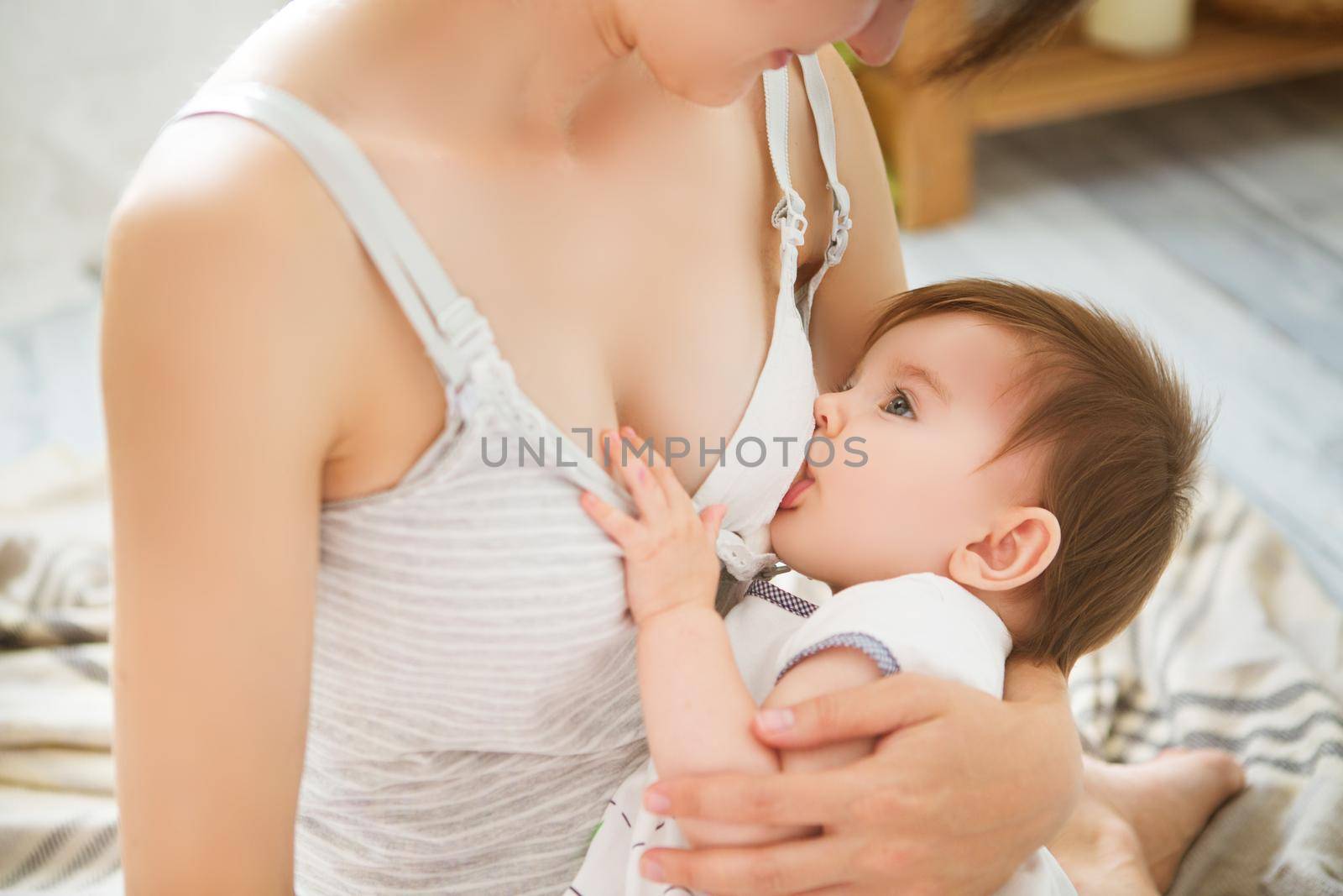 Mother breastfeeding baby in her arms at home. Mom breast feeding her newborn child. Baby eating mother's milk. Concept of lactation infant.