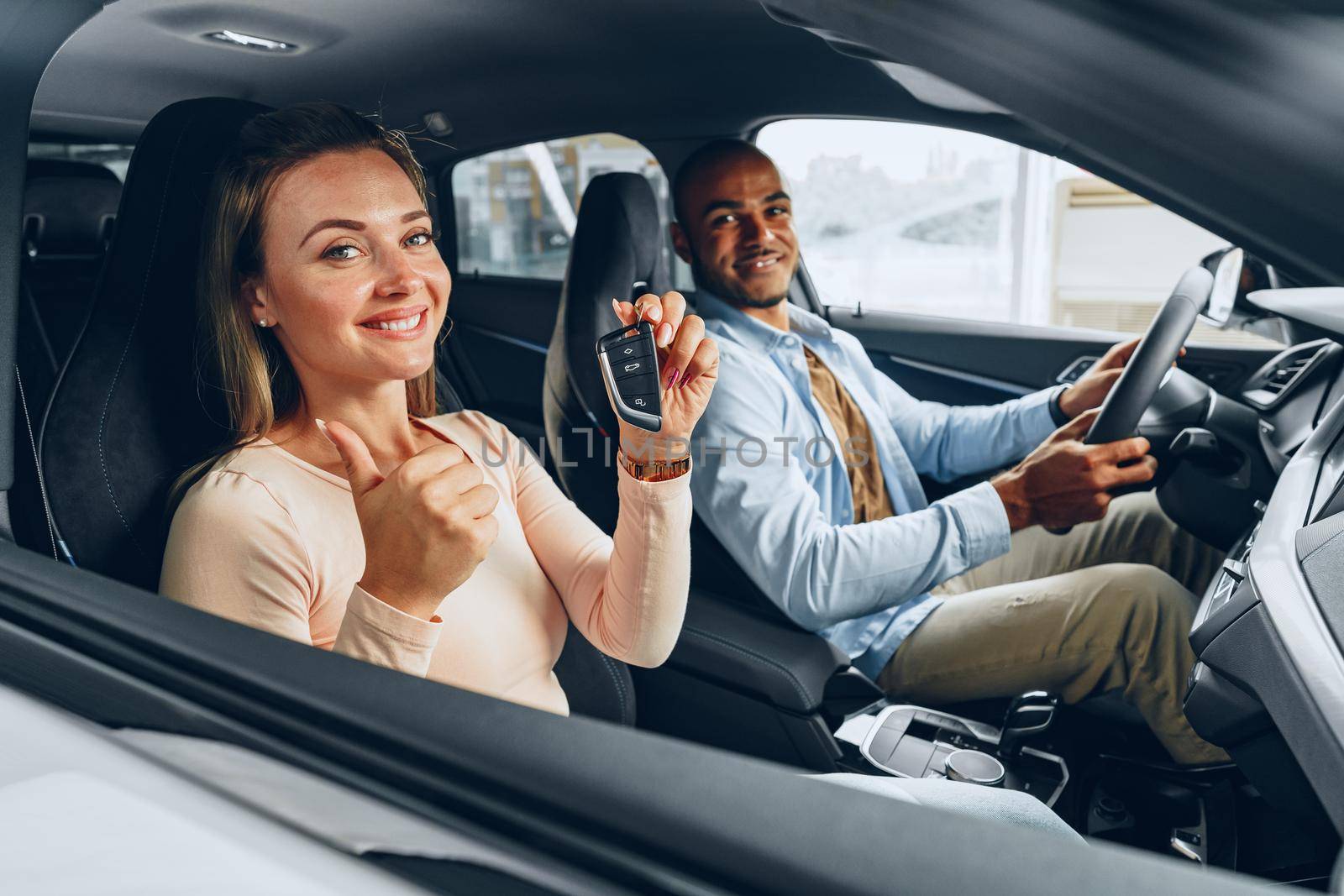 Happy excited couple or family buying a new car and showing keys