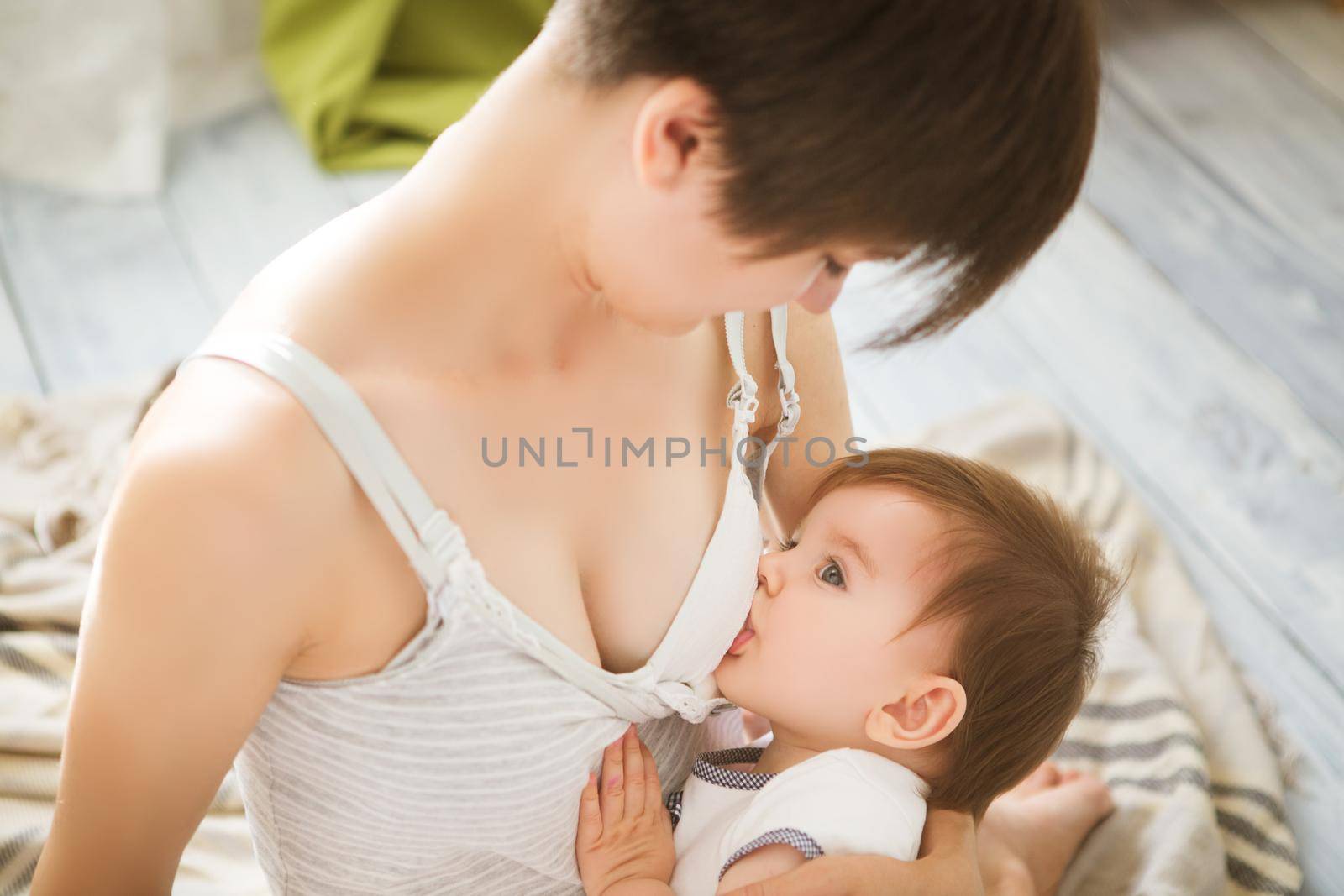 Mother breastfeeding baby in her arms at home. Mom breast feeding her newborn child. Baby eating mother's milk. Concept of lactation infant.