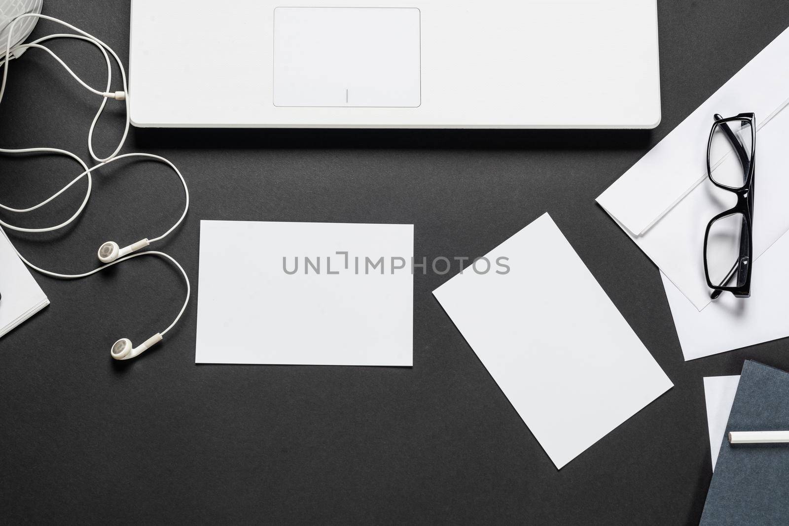 Still life of workplace with office supplies. Flat lay with laptop computer, notepad and eyeglasses on black surface. Top view marketing specialist workspace. Digital technology and mobility lifestyle