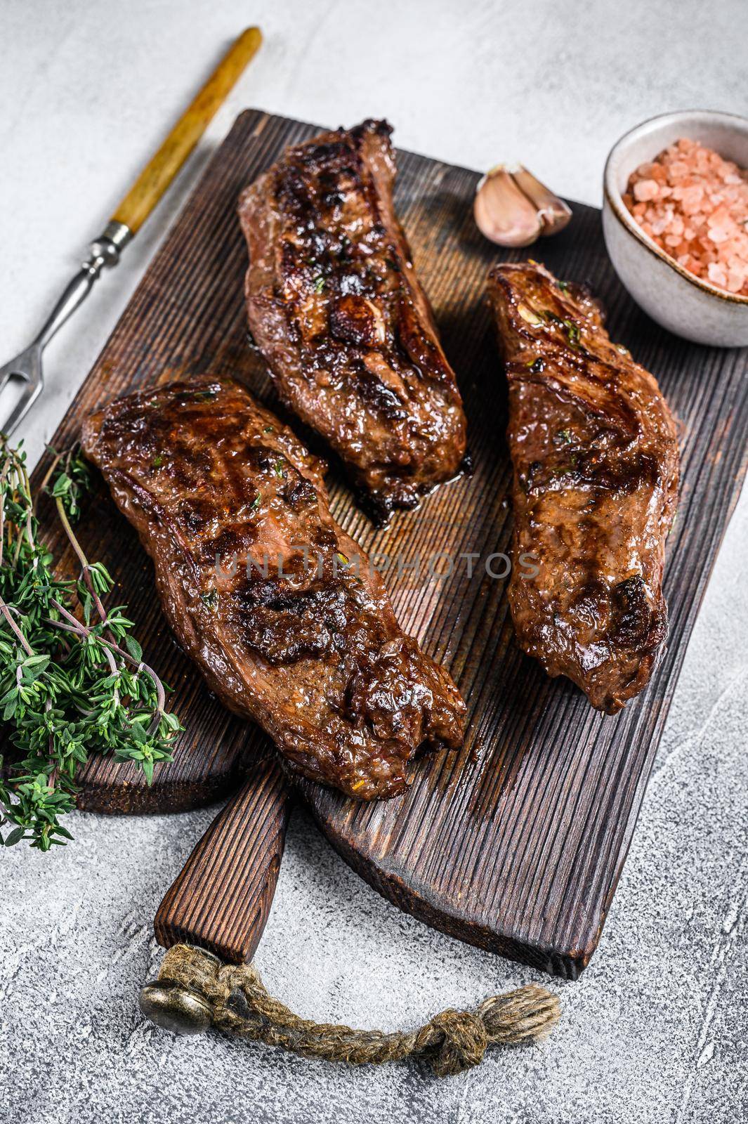 Grilled brisket steaks in bbq sauce on a wooden board. White background. Top view by Composter