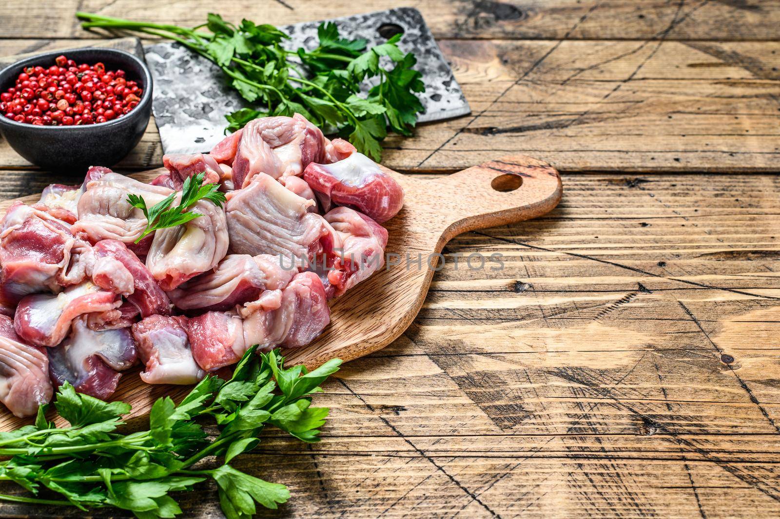 Raw uncooked chicken gizzards, stomach on a cutting board. wooden background. Top view. Copy space by Composter