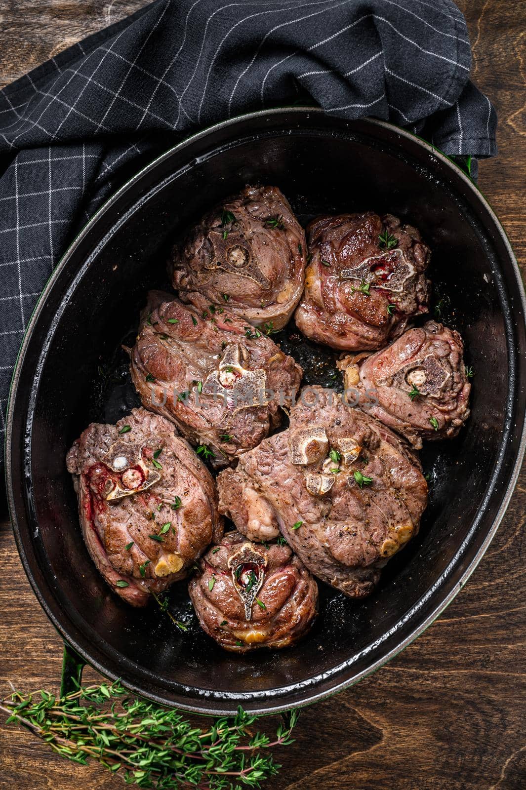 Stewed lamb neck meat in a pan with herbs. wooden background. Top view by Composter