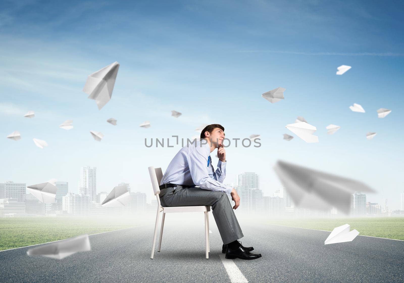 young businessman sits on an office chair, thoughtful and looking up