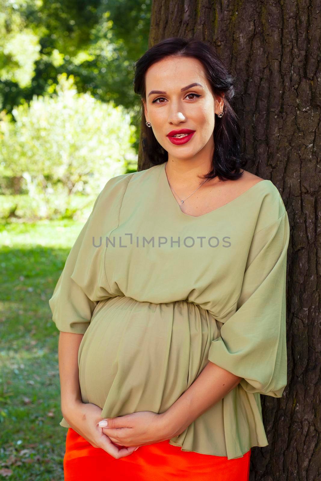 young pretty brunette pregnant woman outdoor in green park happy smiling, lifestyle people concept close up