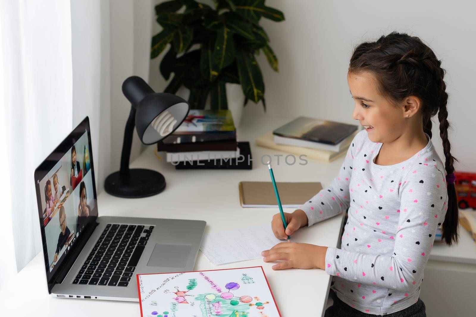 Little girl studying online using her laptop at home