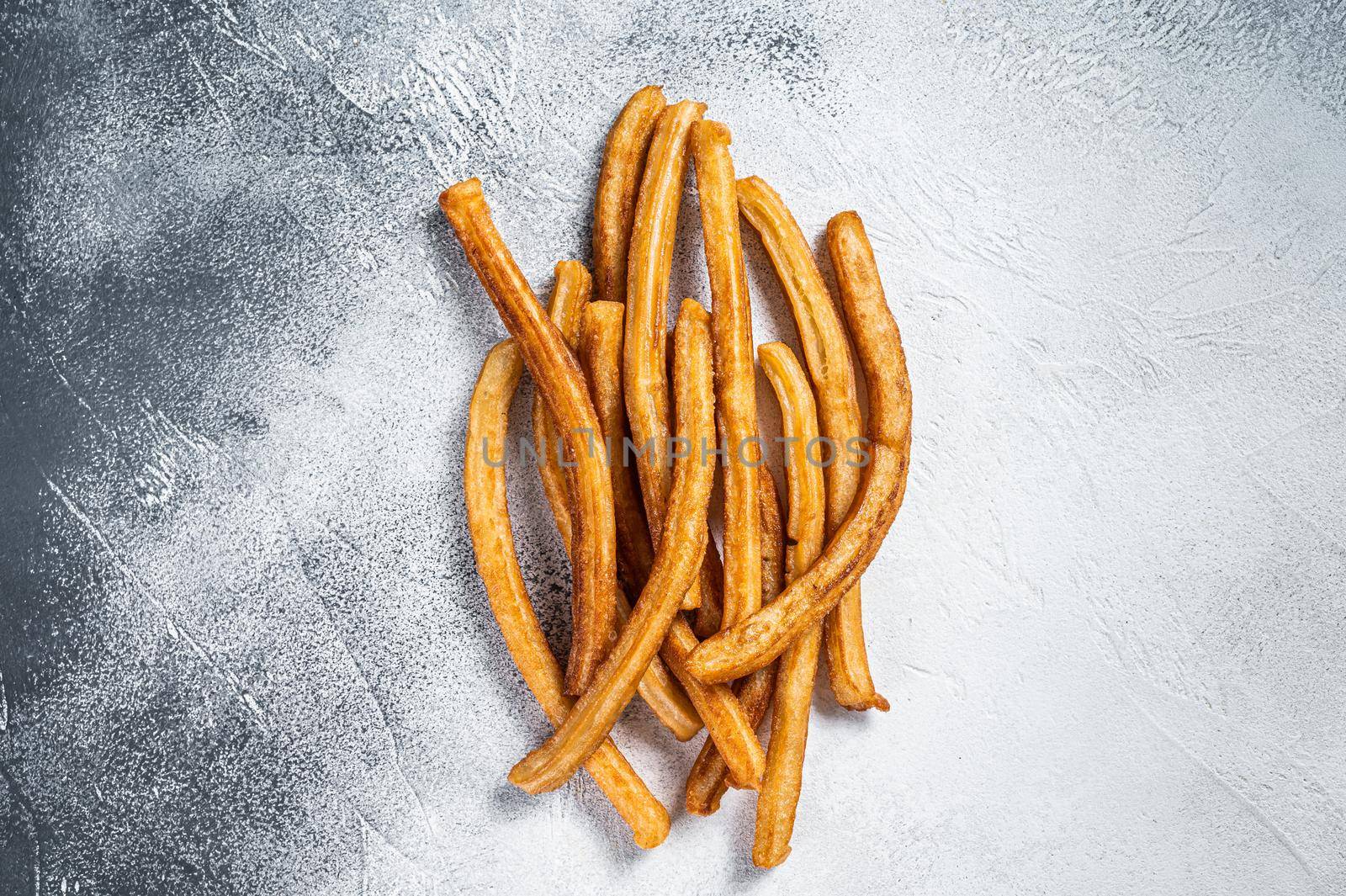 Churros fried sticks on kitchen table. White background. Top view by Composter