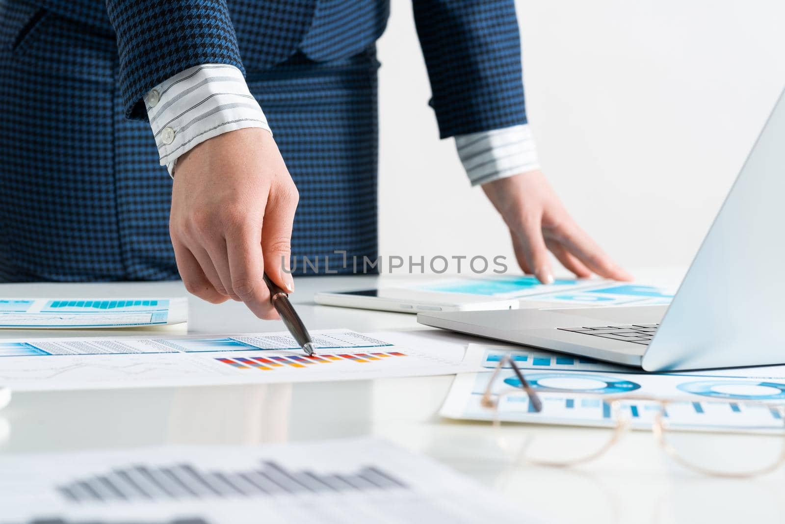 Businesswoman standing near office desk with laptop and documents. Financial audit and consulting. Corporate manager in suit working with online business analytics. Investment and stock trading