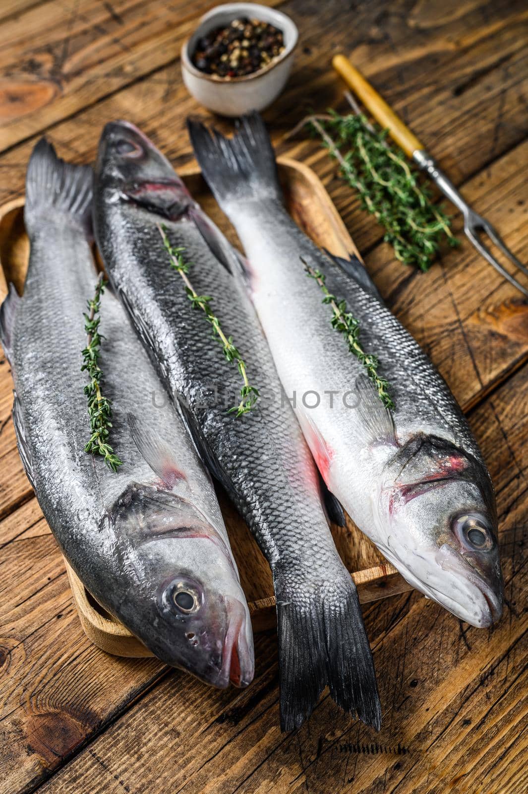 Raw seabass fish on a tray. wooden background. Top view.