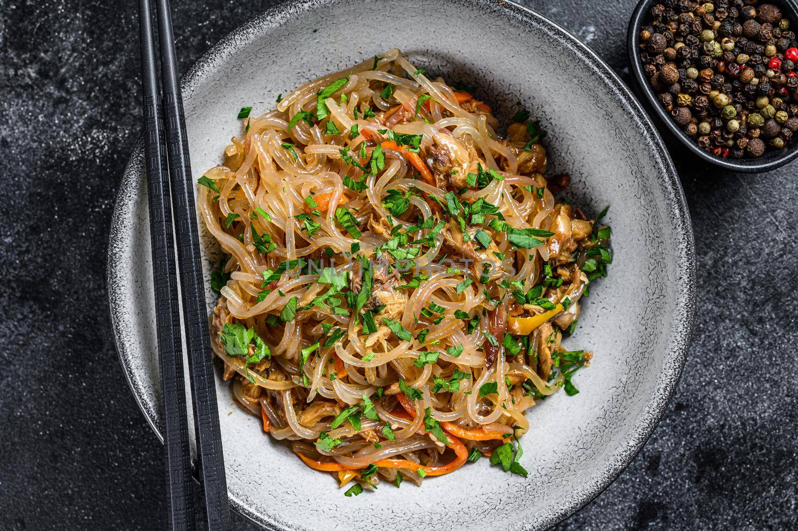 Wok Hot Asian cellophane noodles with chicken meat. Black background. Top view by Composter