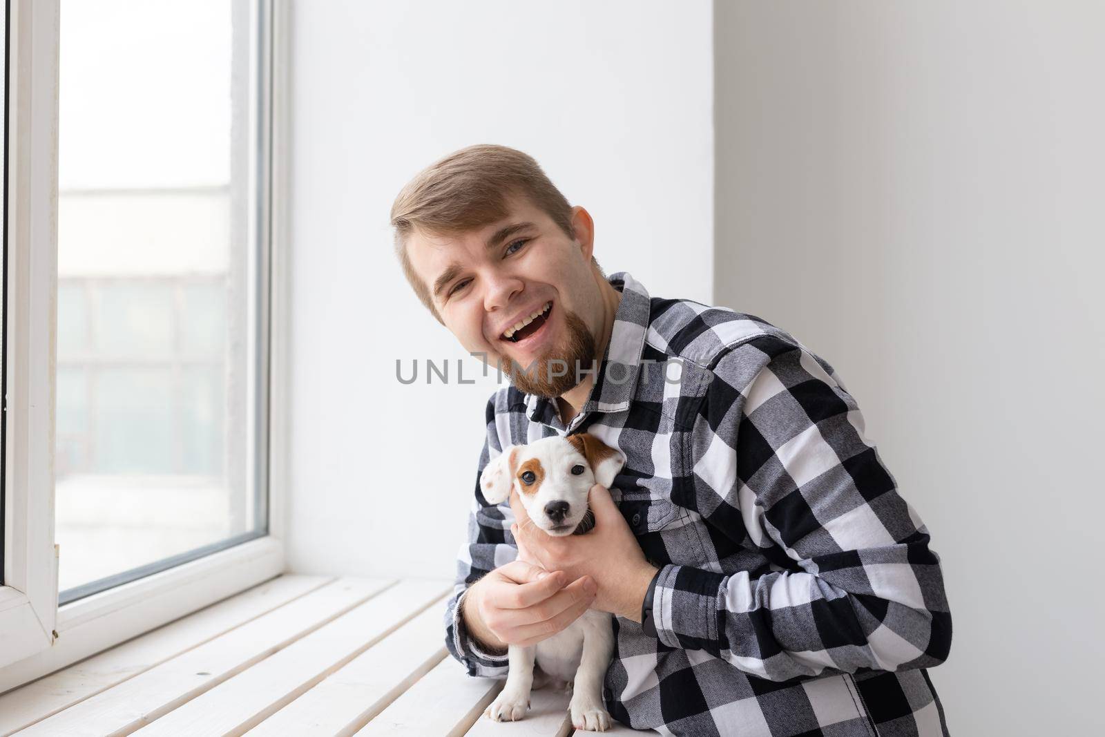 people, pets and animals concept - young man hugging jack russell terrier puppy by Satura86