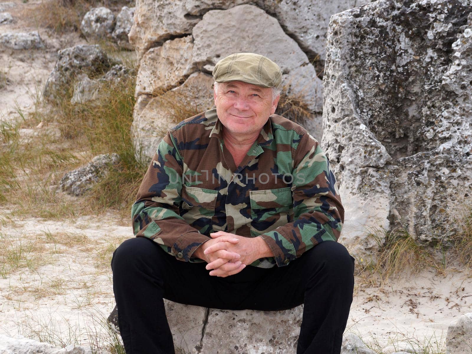 smiling middle aged man sitting on a stone, portrait