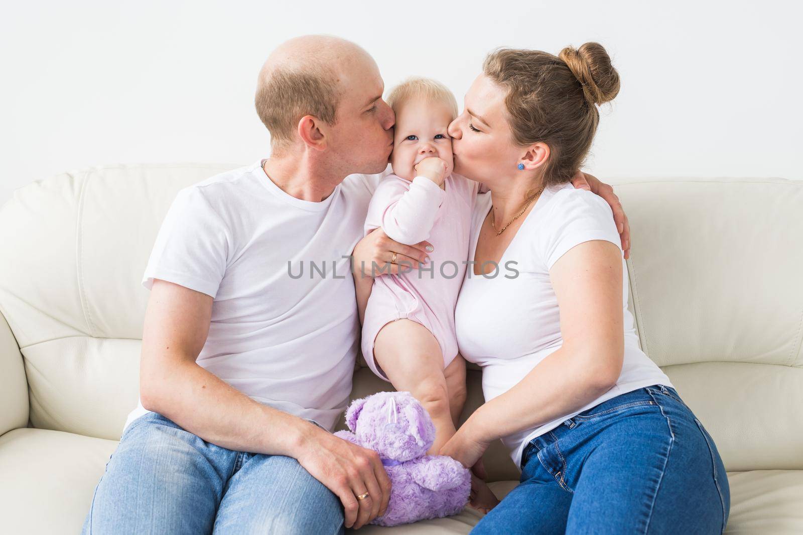 Smiling mother and father holding their newborn baby daughter at home