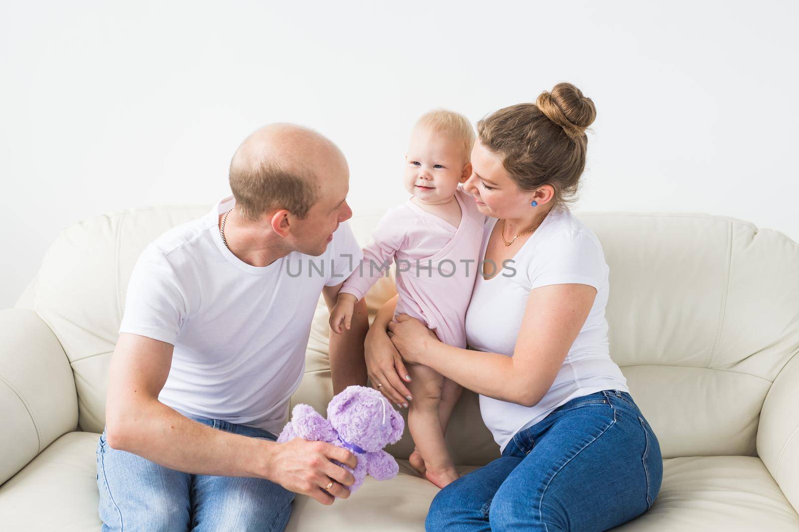 Smiling mother and father holding their newborn baby daughter at home