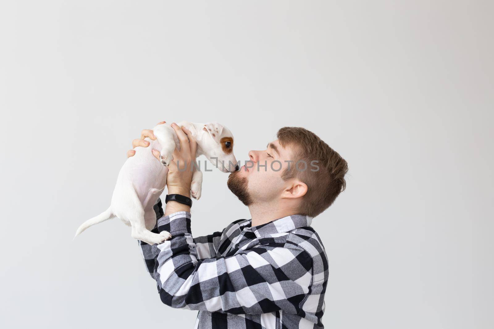 people, pets and animals concept - close up of young man holding jack russell terrier puppy on white background by Satura86