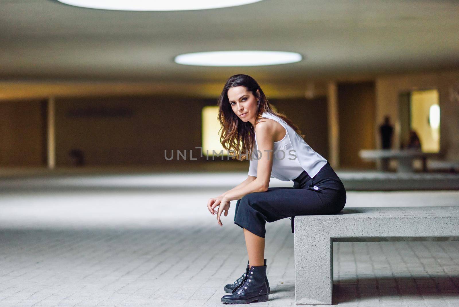 Beautiful brunette woman, model of fashion, posing in modern building with casual clothes.