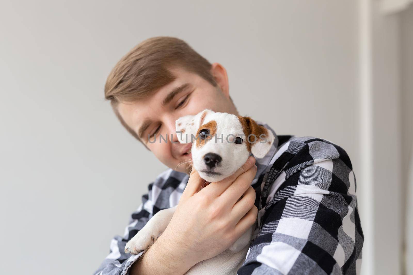 people, pets and animals concept - close up of young man hugging jack russell terrier puppy on white background by Satura86
