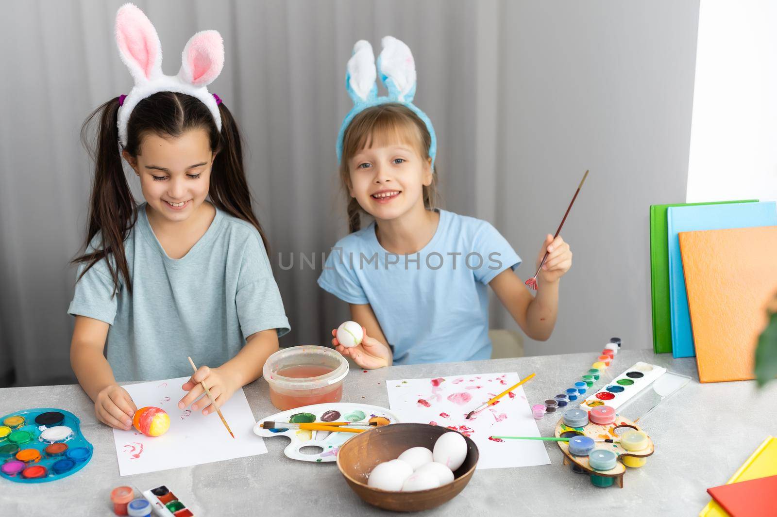 Happy easter. Two sisters painting Easter eggs. Happy family children preparing for Easter. Cute little child girl wearing bunny ears on Easter day.