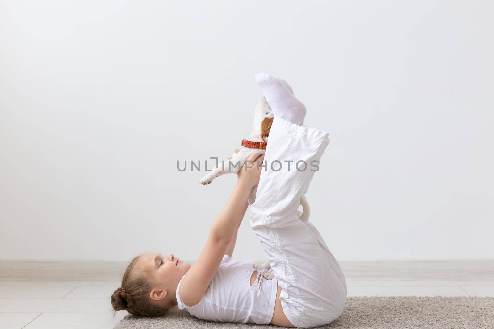 people, children and pets concept - little kid girl lying on the floor with cute puppy Jack Russell Terrier by Satura86