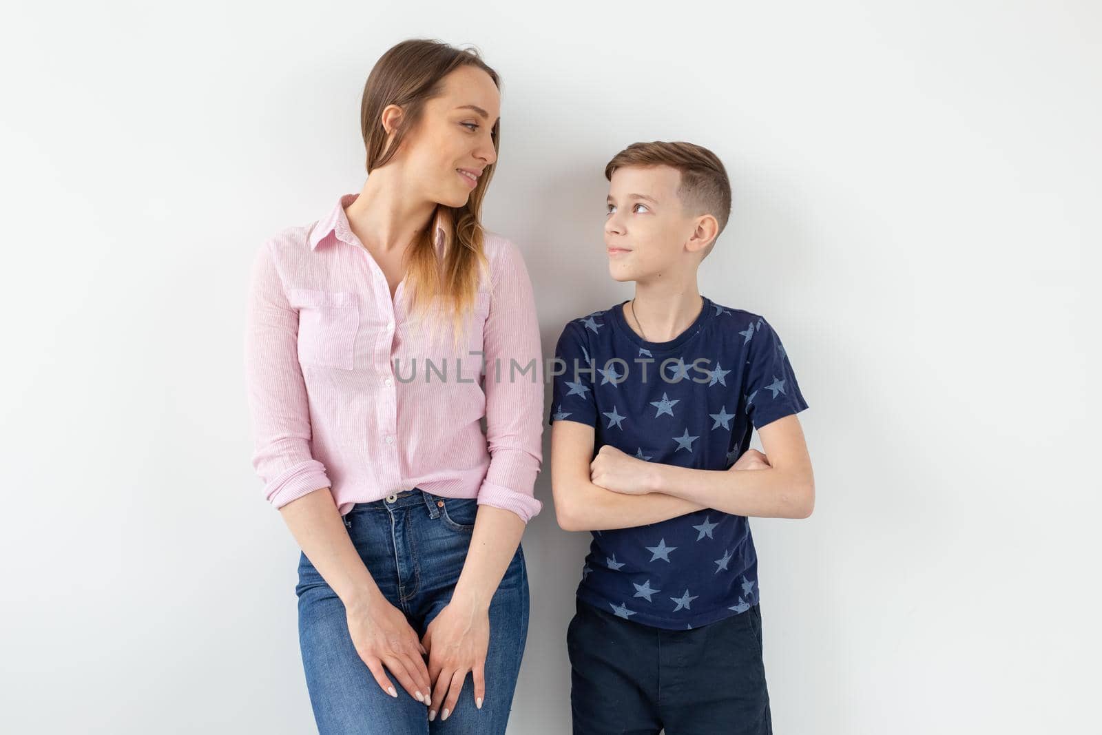 Charming young mother and a cute positive son are happy looking at each other while standing in the new living room after the move. The concept of good family relationships and relocation