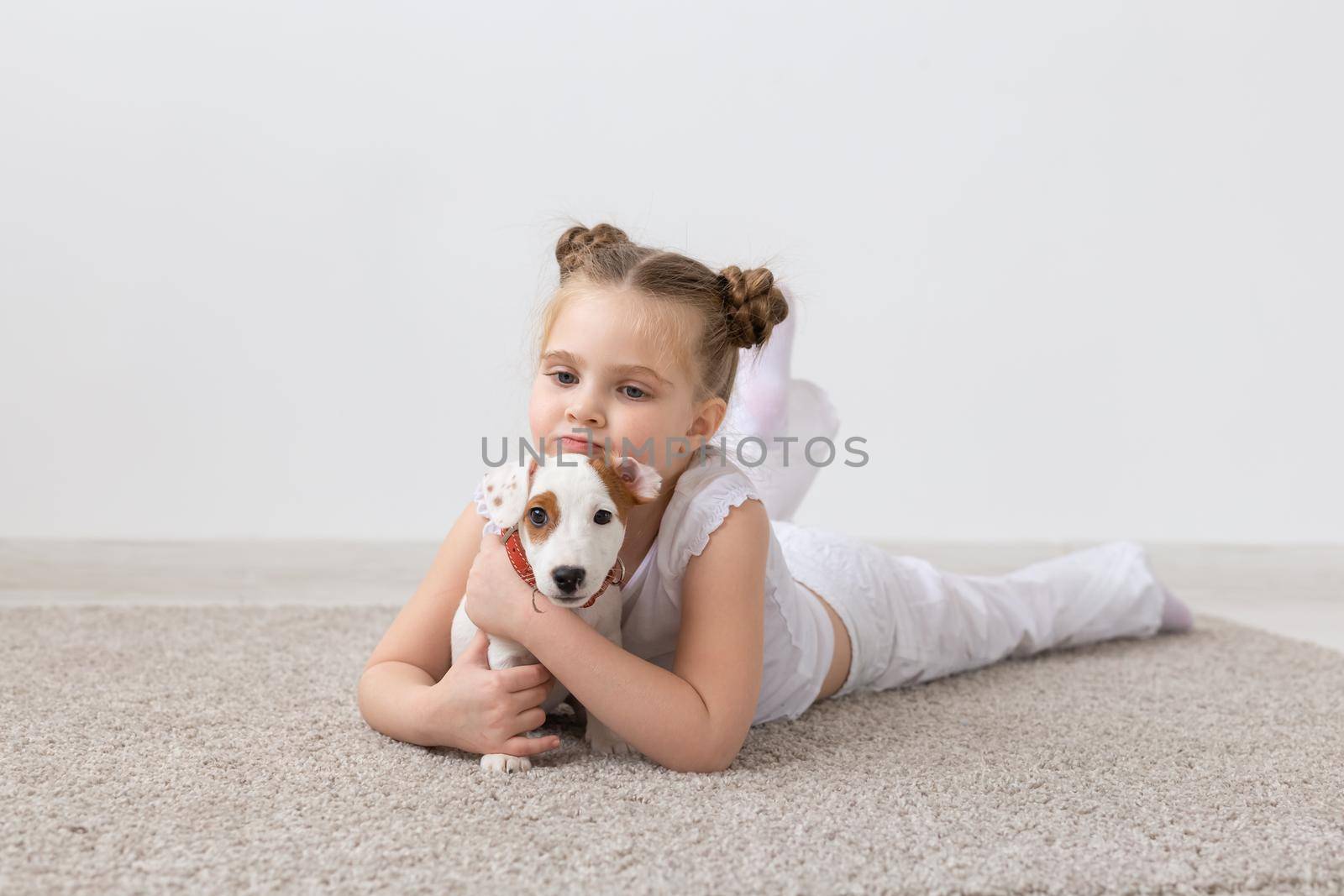 people, children and pets concept - little child girl lying on the floor with cute puppy Jack Russell Terrier by Satura86