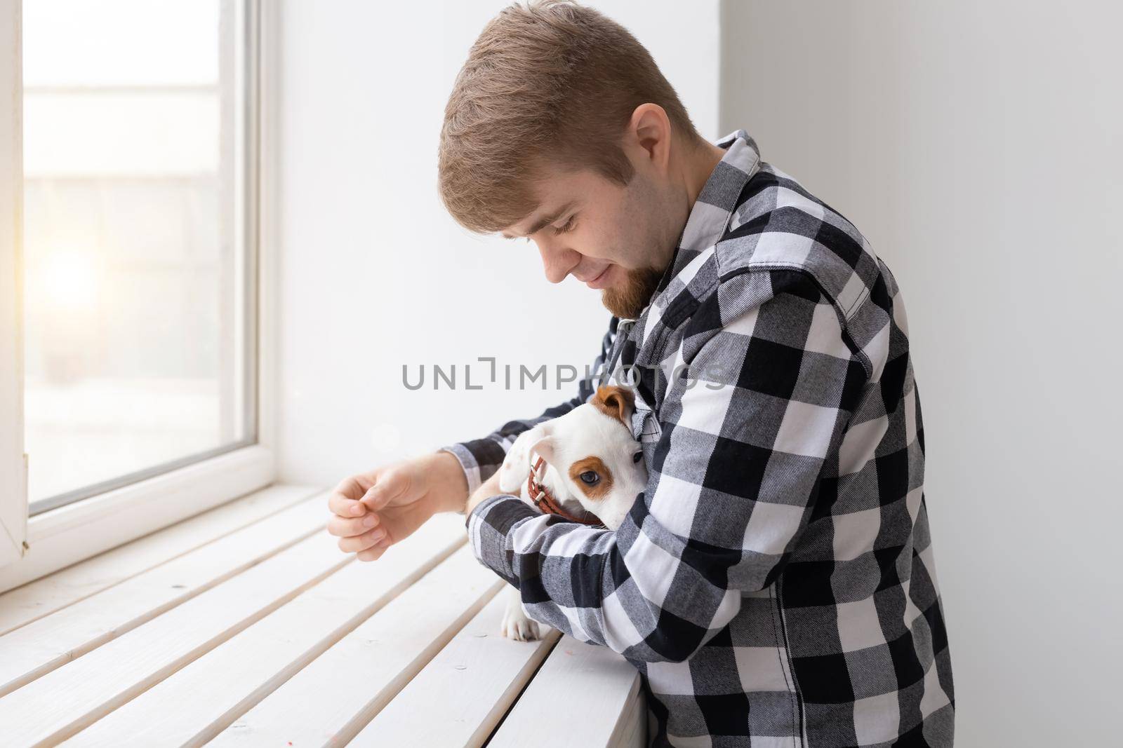 people, pets and animals concept - young man hugging puppy on white background.