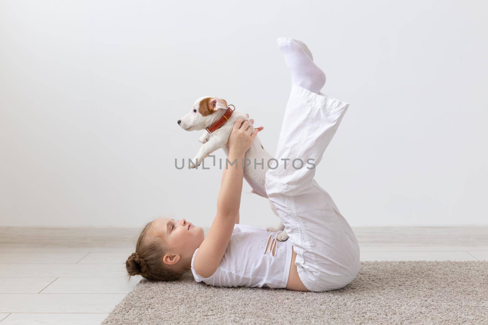 people, children and pets concept - little kid girl lying on the floor with cute puppy Jack Russell Terrier by Satura86