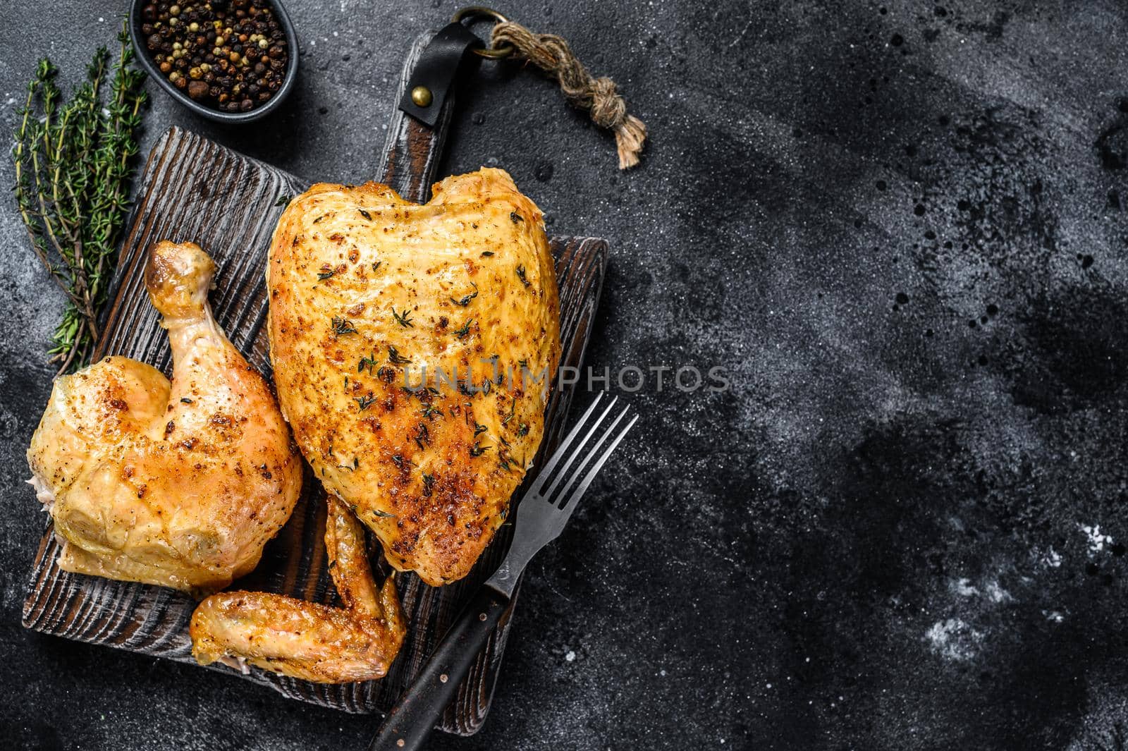 Butchered grilled whole chicken. Black background. Top view. Copy space.