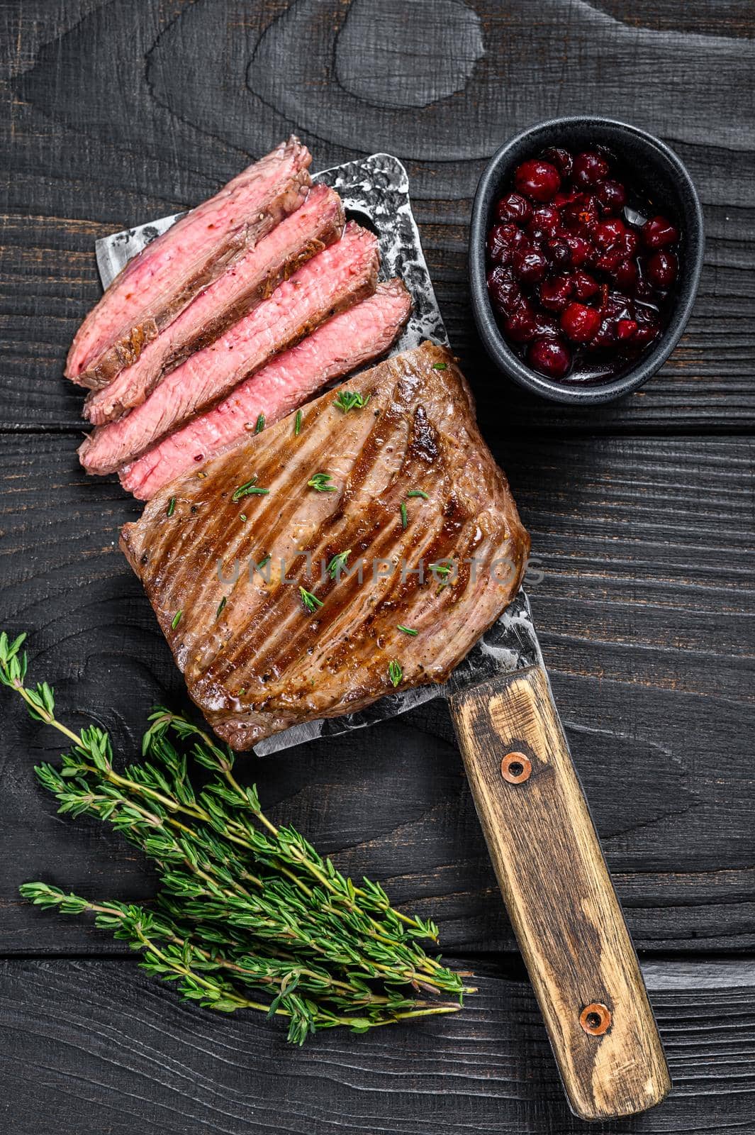 Sliced skirt beef meat steak on a cleaver. Black wooden background. Top view by Composter