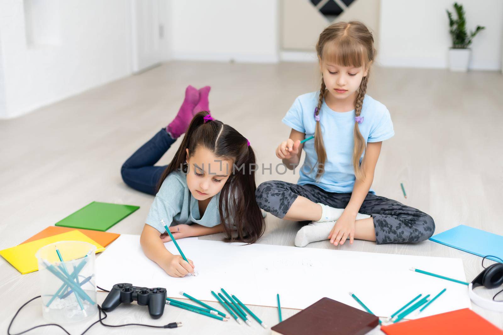 Cute children are painting and smiling while lying on the floor at home