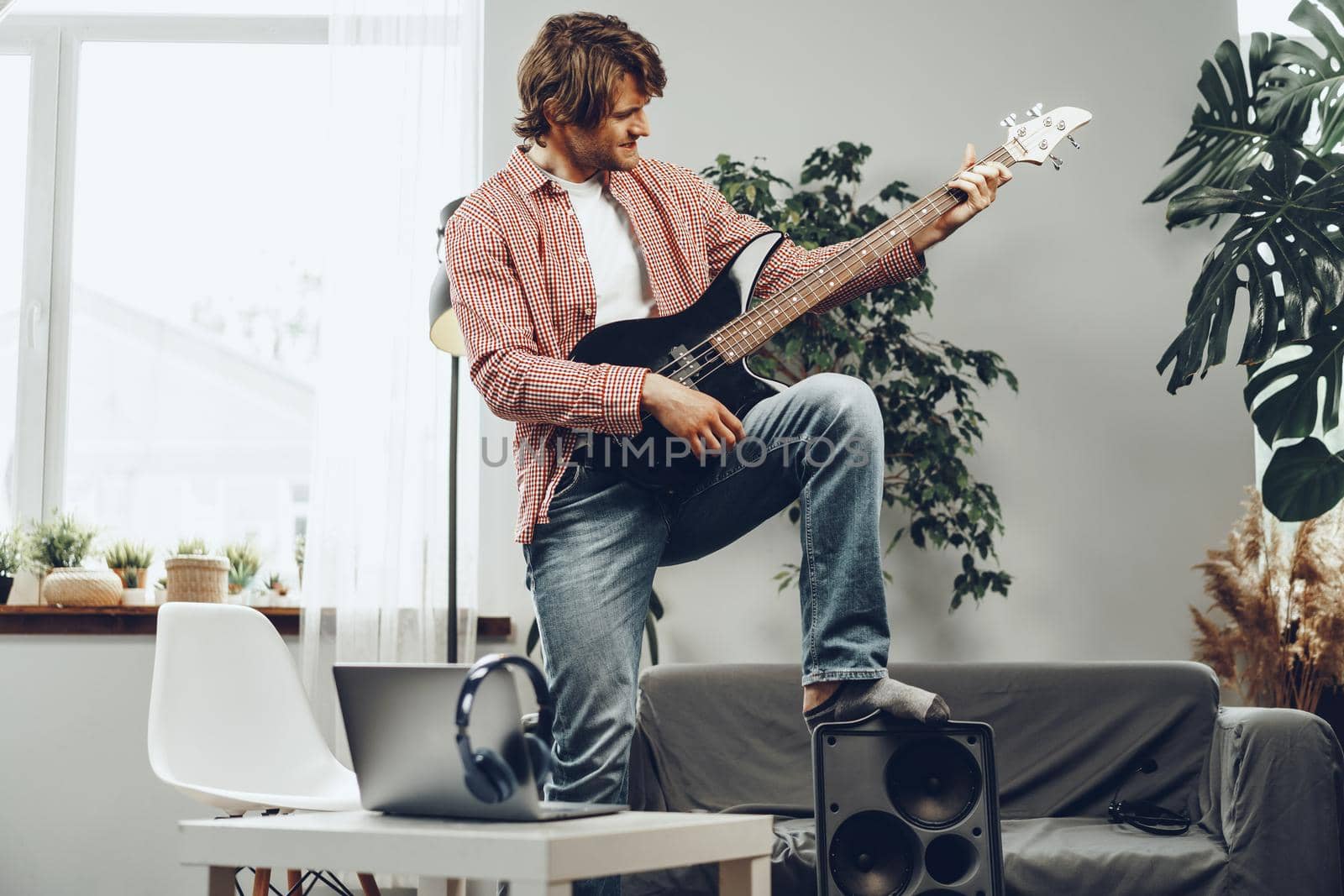 Man playing electric guitar and recording music into laptop at home