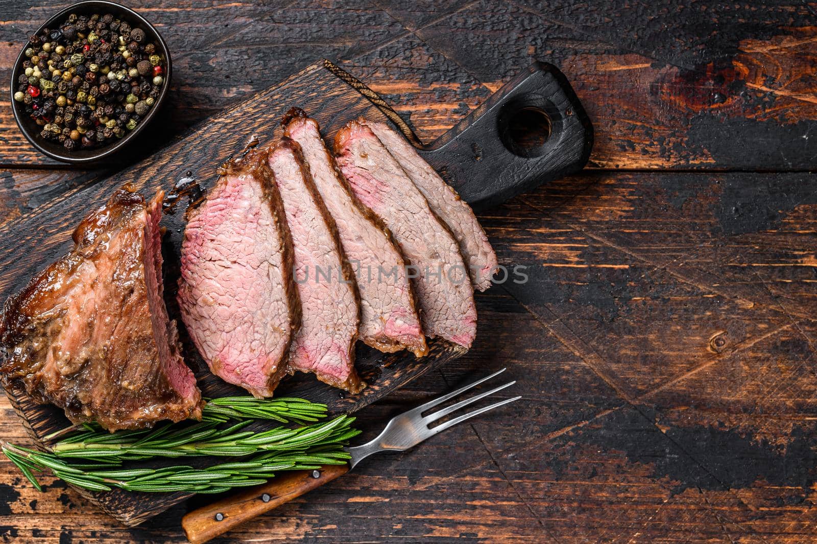 Sliced Roast beef sirloin tri tip steak bbq. Dark wooden background. Top view. Copy space.