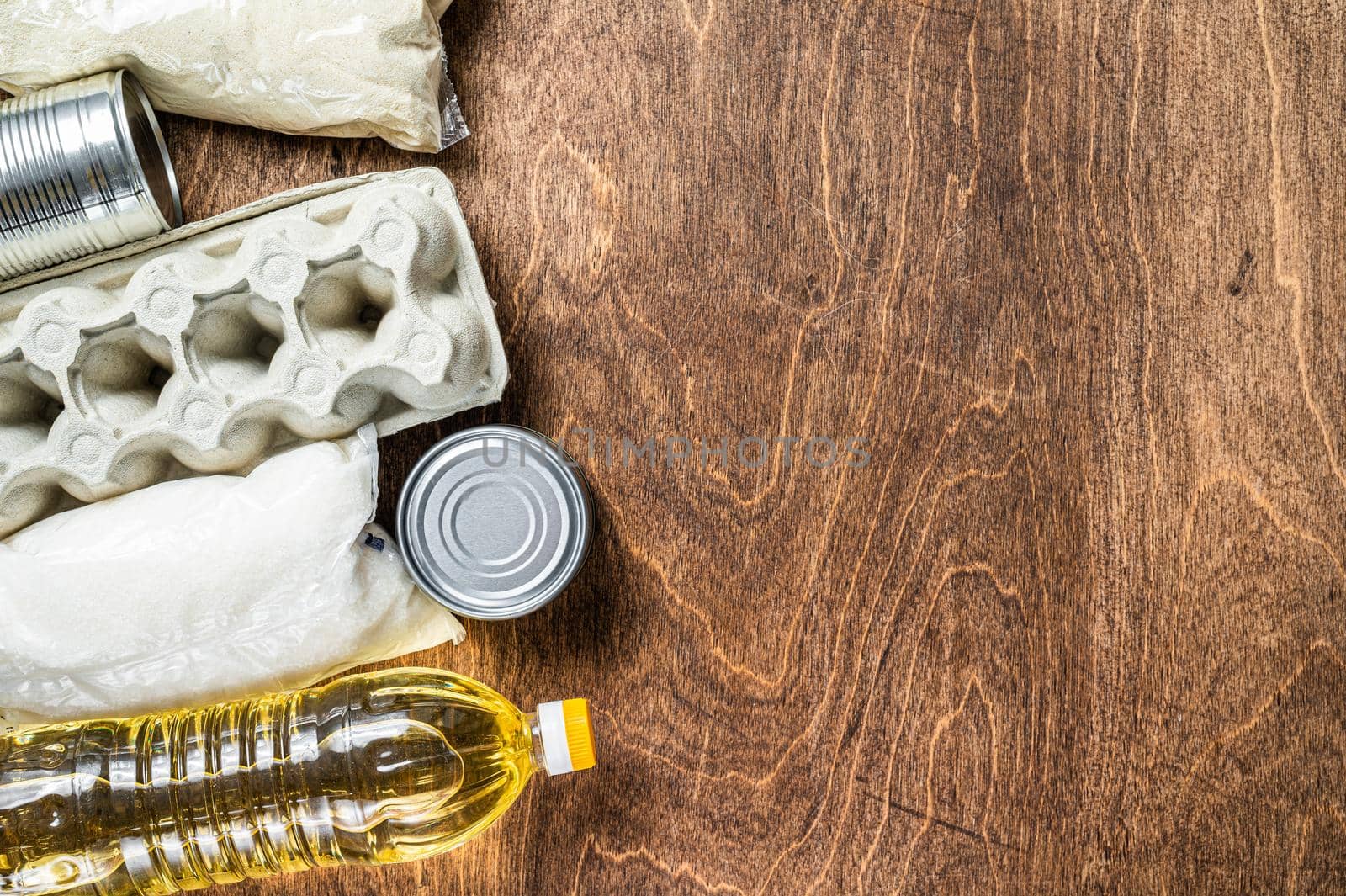 Food delivery Donation, quarantine help concept. Oil, canned food, pasta, bread, sugar, egg. Wooden background. Top view. Copy space.