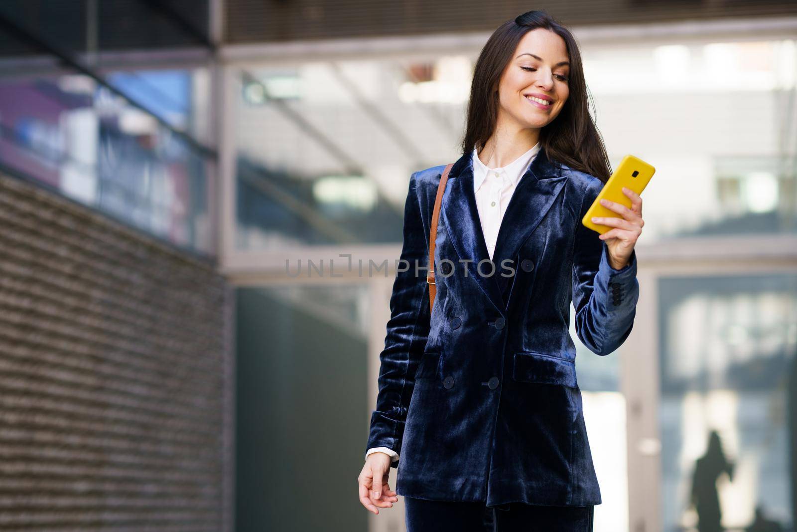 Business woman wearing blue suit using smartphone in an office building. Lifestyle concept.
