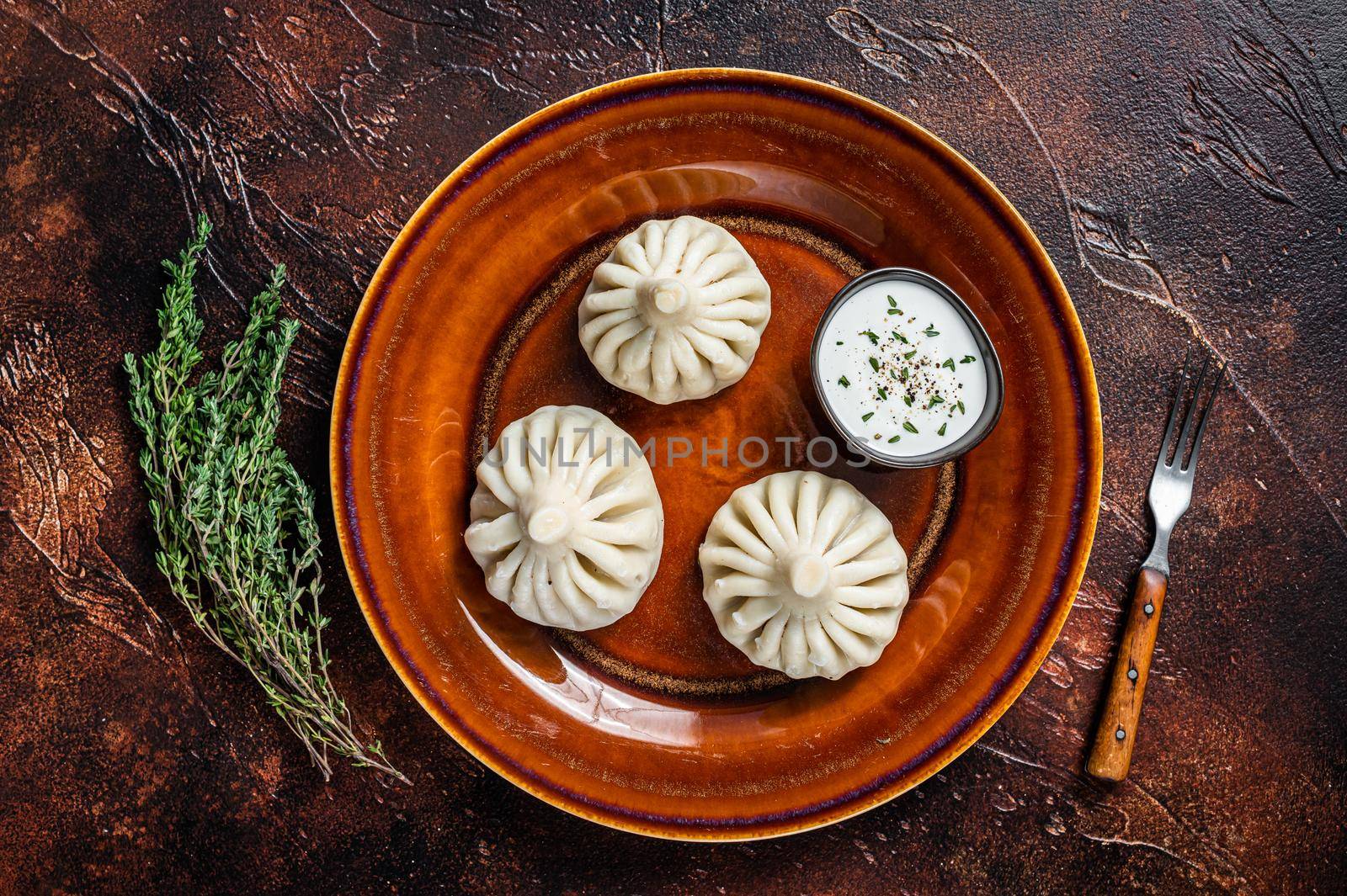 Khinkali Dumplings with beef and lamb meat on rustic plate with herbs. Dark background. Top view.
