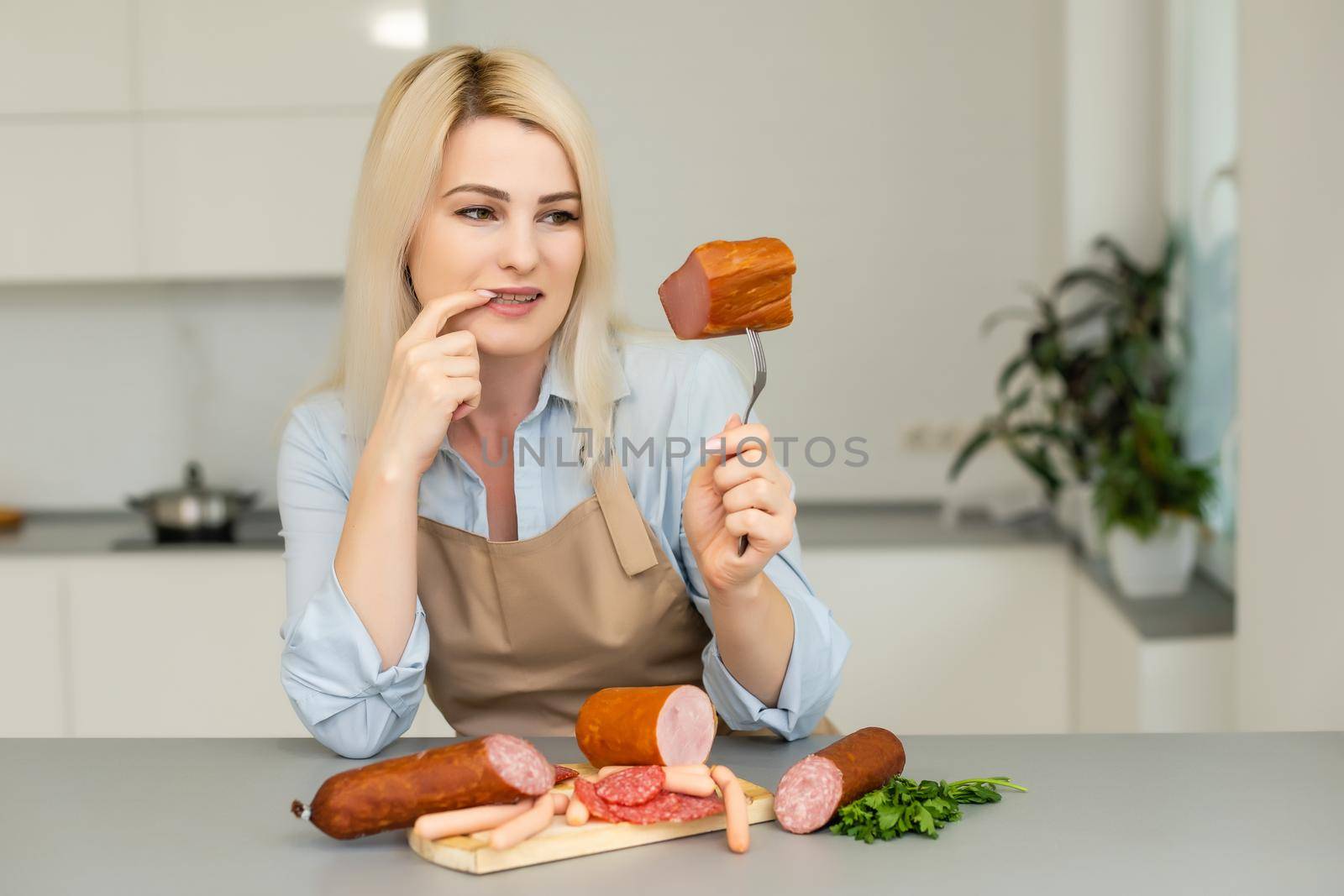 The girl is eating sausage. A piece of sausage. Smile and Joy. Business concept is the brand's appeal. Appetite