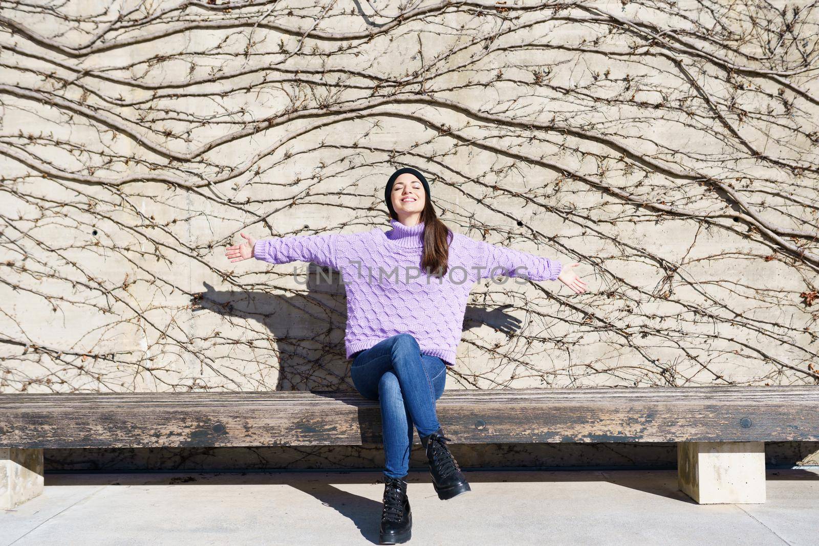 Happy young woman smiling with eyes closed and open arms outdoors. Lifestyle concept.