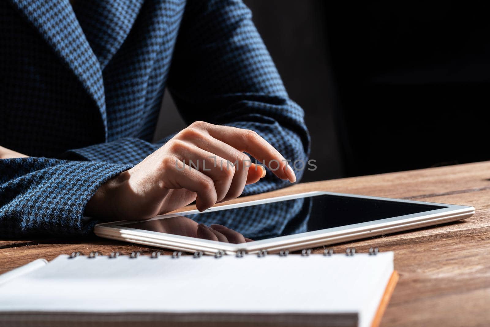 Businesswoman using tablet computer at desk. Close up woman hand pointing on touchscreen. Online stock trading and financial analytics. Digital technology in strategy planning and company management