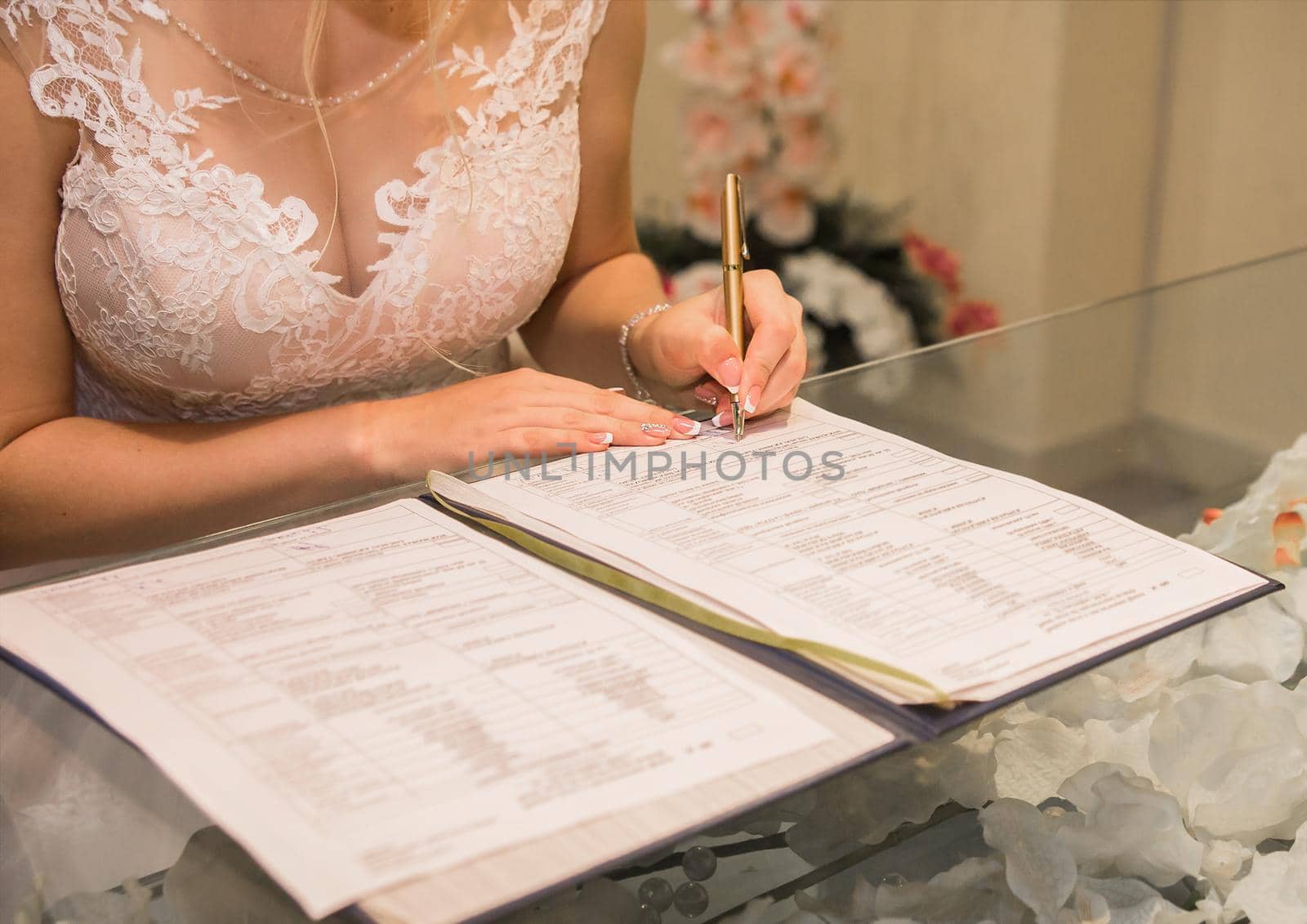 Young bride's hands put signature on consent to marriage close-up.