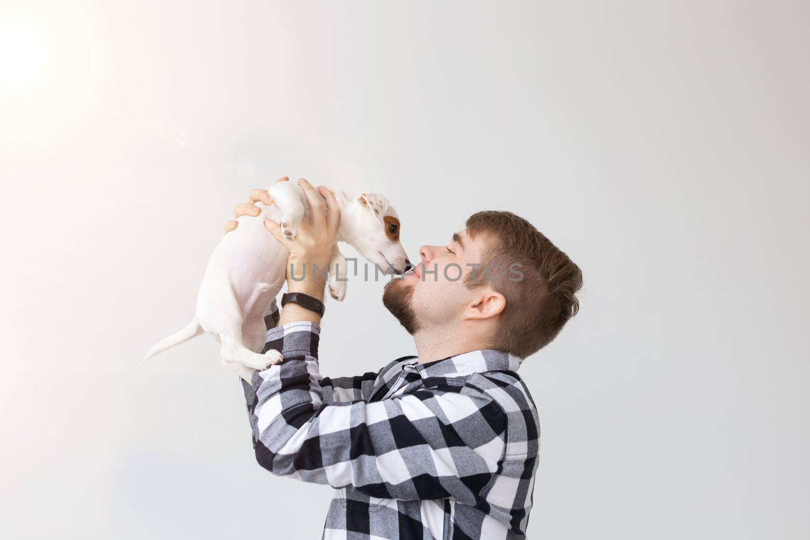 people, pets and animals concept - young man holding jack russell terrier puppy on white background by Satura86