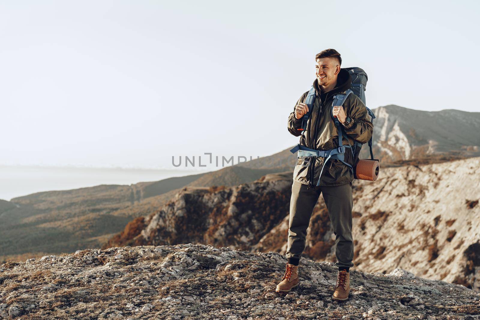 Young caucasian man traveler with big backpack hiking in the mountains alone