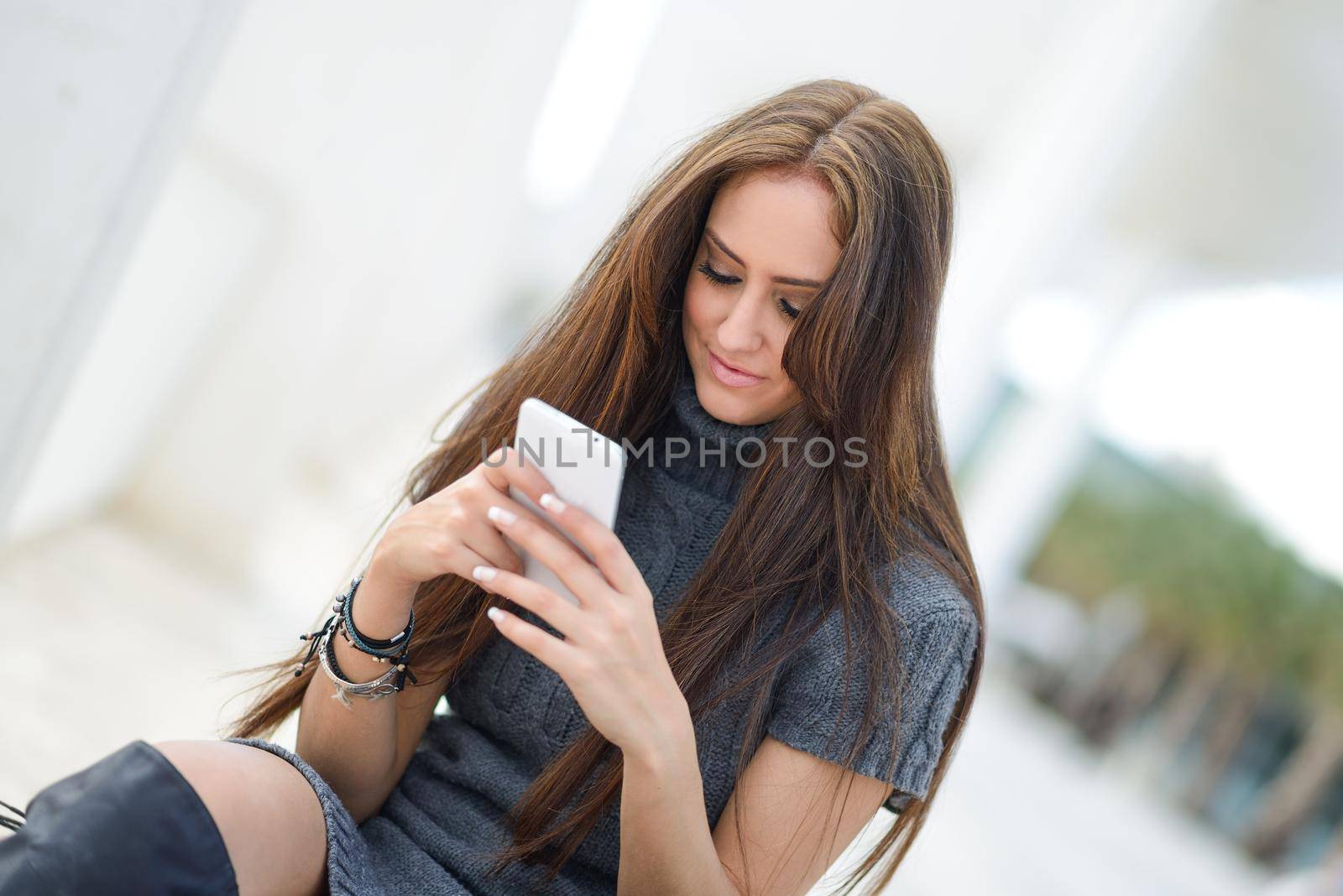 Portrait of beautiful young woman in urban background writting on phone