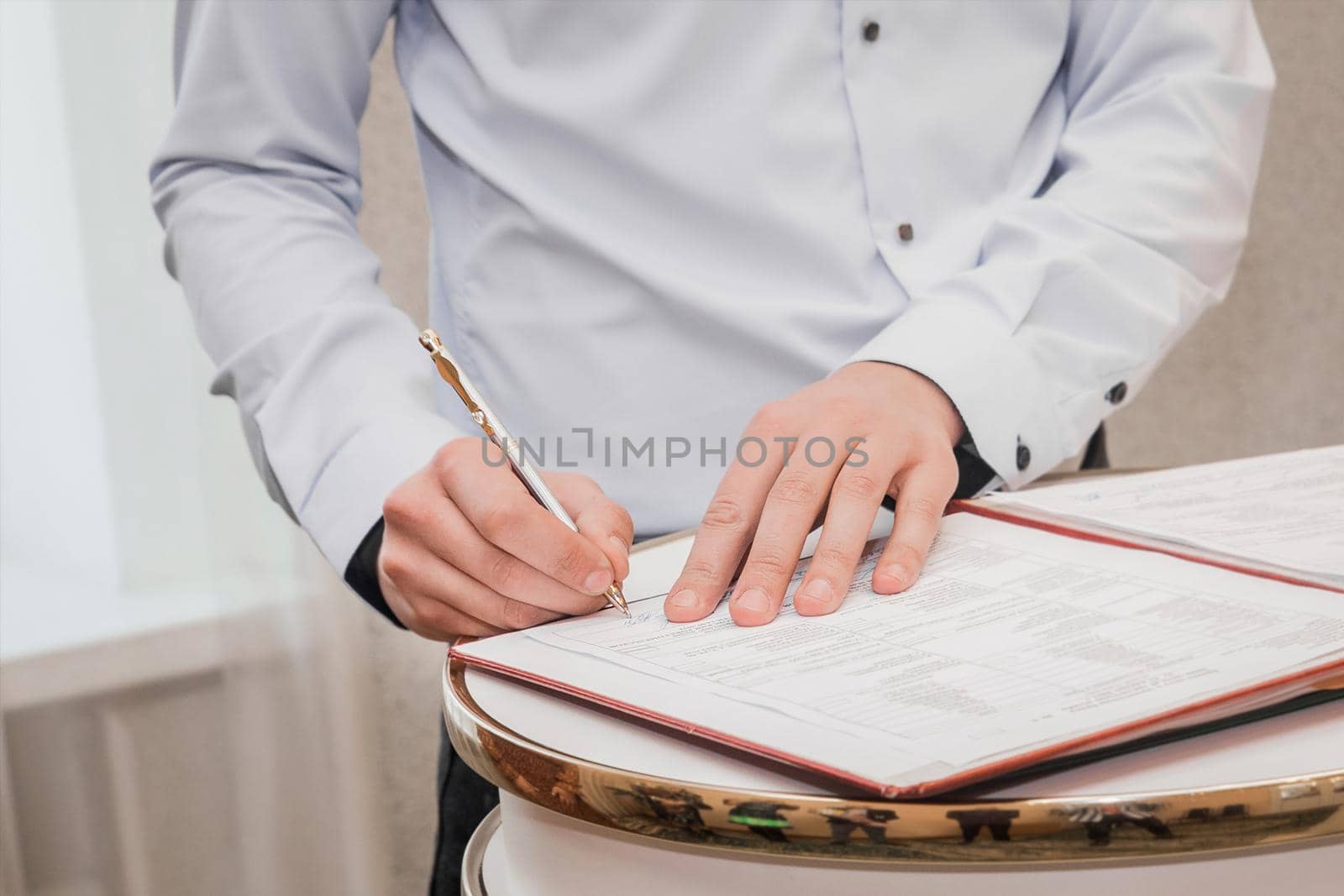 The hands of the witness's boyfriend in the shirt put the signature on the wedding close-up.