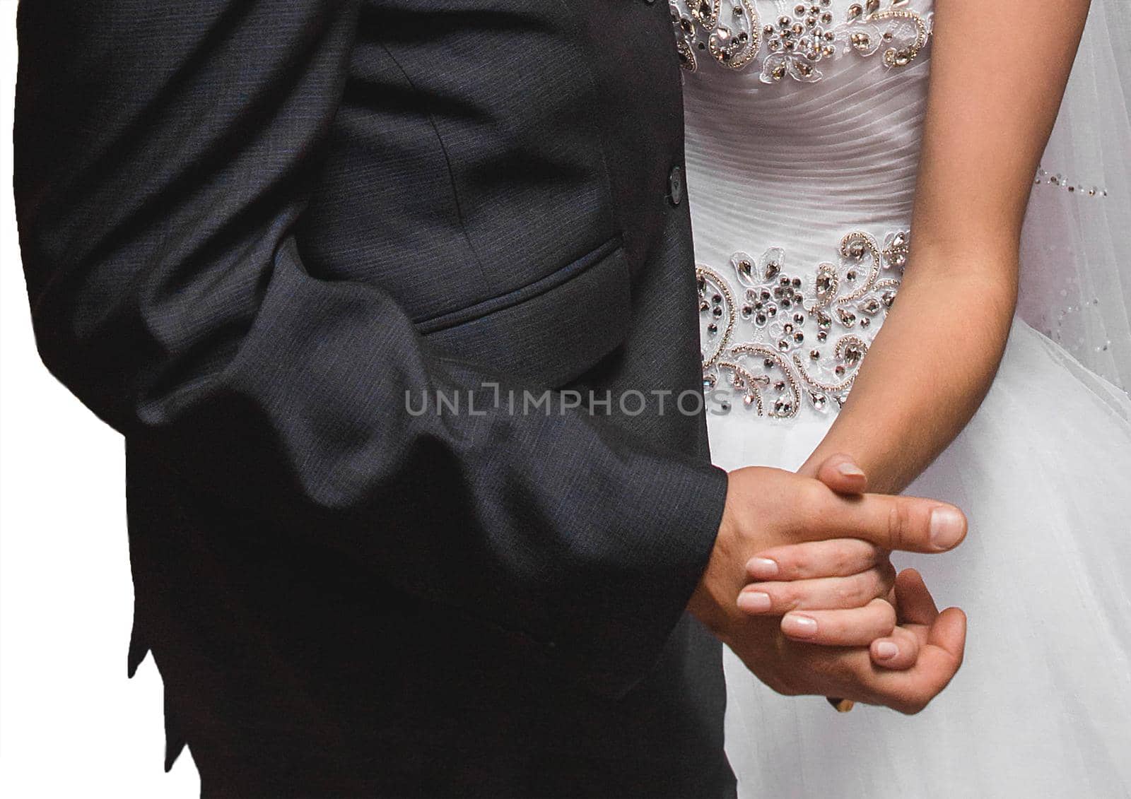 The bride and groom hold hands together tightly close-up at the wedding.
